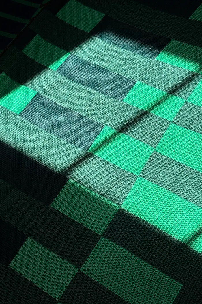 Modern knit blanket featuring a bold grid design in dark and light green.
