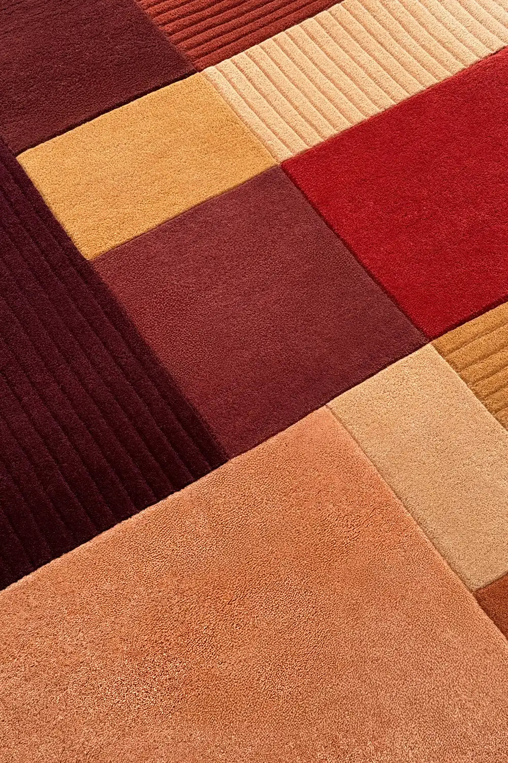 Hand-tufted wool rug featuring sculpted texture and warm modern color block sections in rust and gold