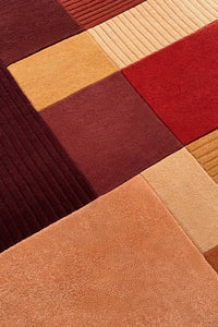 Hand-tufted wool rug featuring sculpted texture and warm modern color block sections in rust and gold