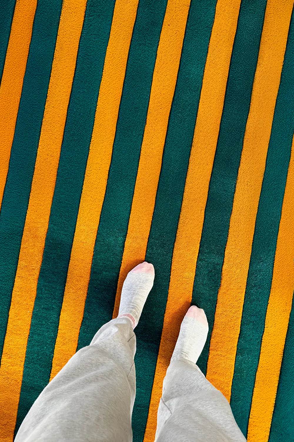 Hand-tufted wool area rug featuring thick green and gold stripes.

