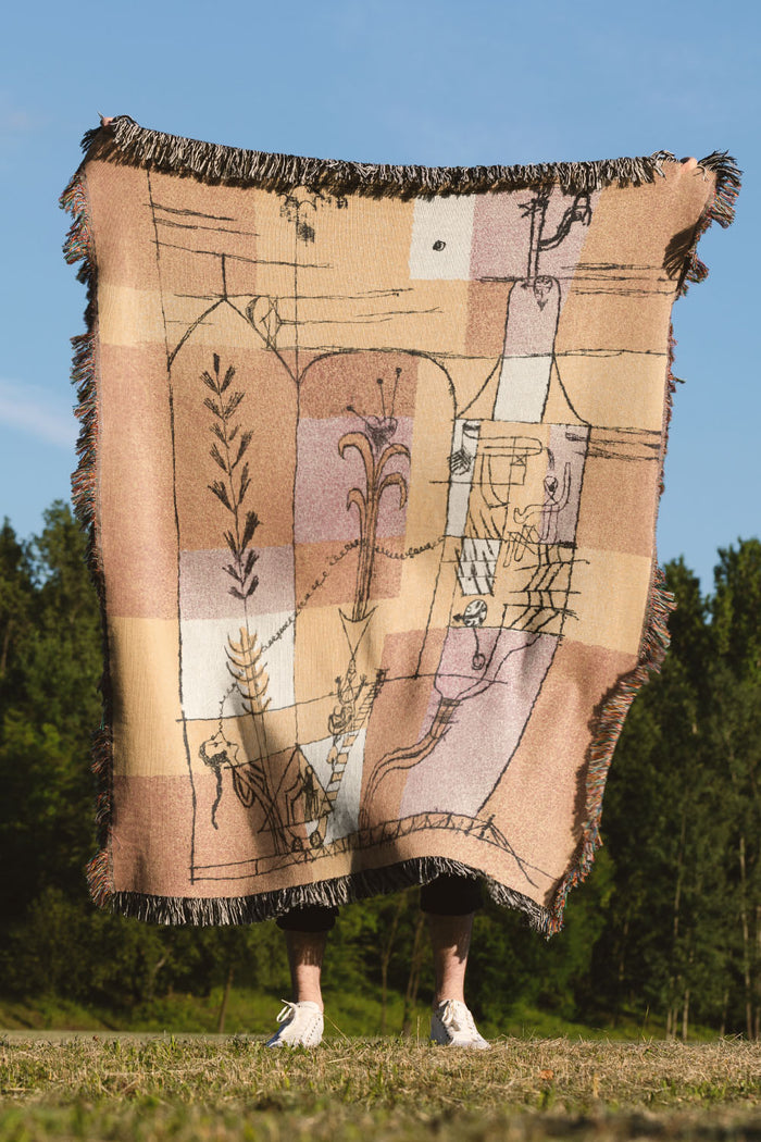 Abstract woven throw blanket in warm yellow, orange, and beige tones with artistic linework.
