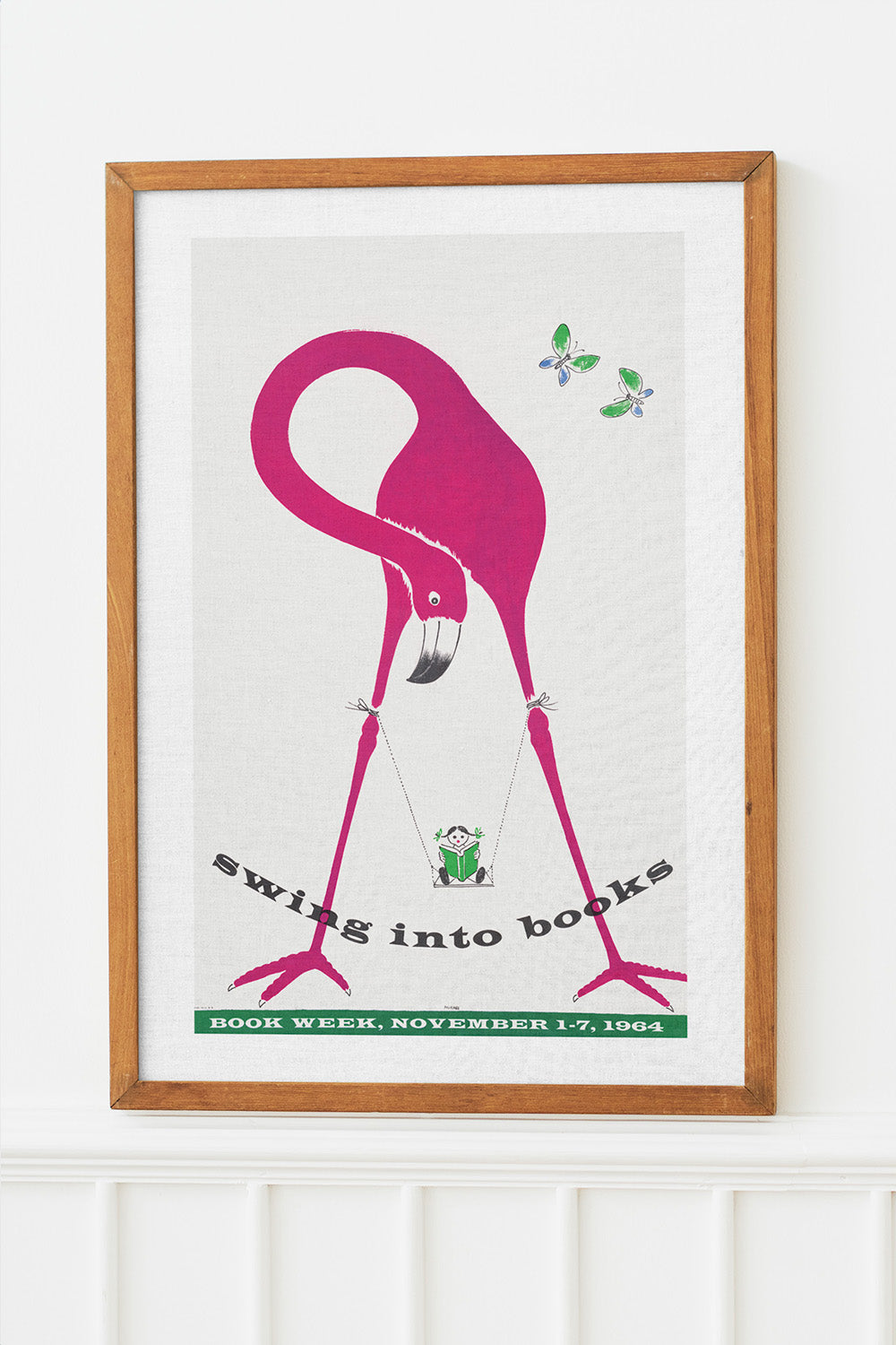 Vintage poster featuring a large pink flamingo with a child swinging between its legs, promoting a book fair.