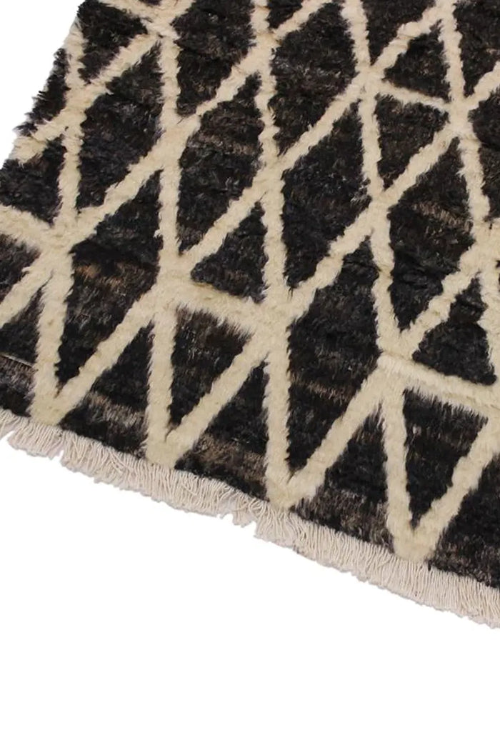 Detailed corner of hand-knotted black and cream shag rug, perfect for large 10x14 living room setups or cozy lounge areas