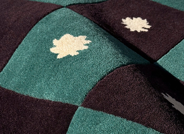 Close-up of a patchwork rug with geometric patterns in green, brown, and white.