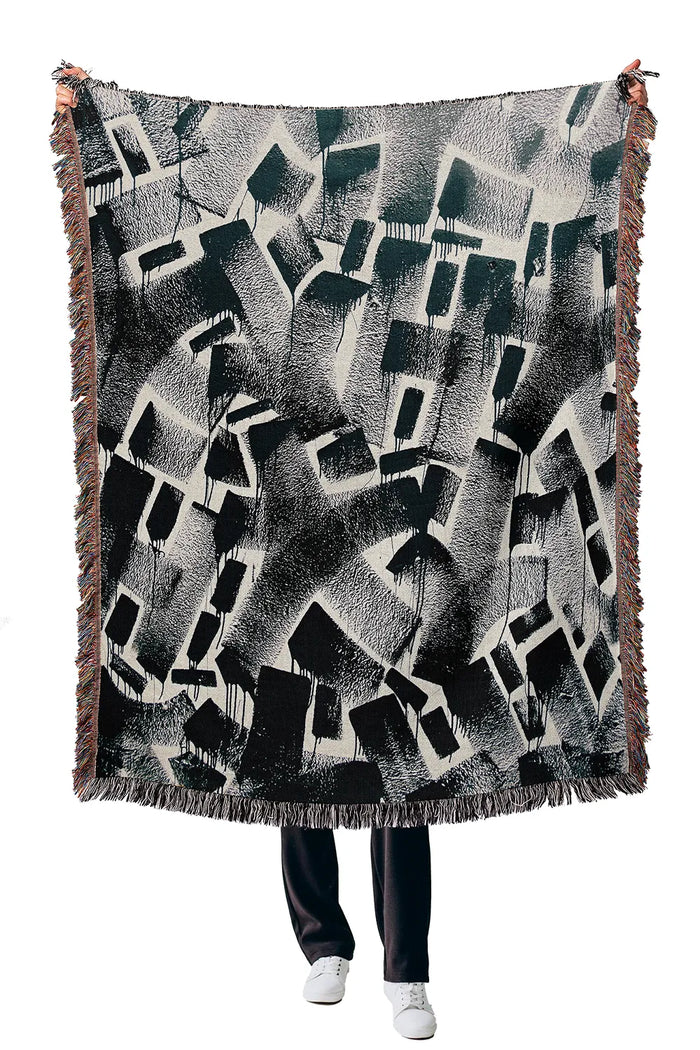Monochrome woven blanket featuring an artistic high-contrast pattern.
