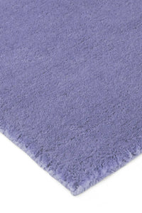 Detail of soft plush purple wool rug with thick, hand-tufted texture