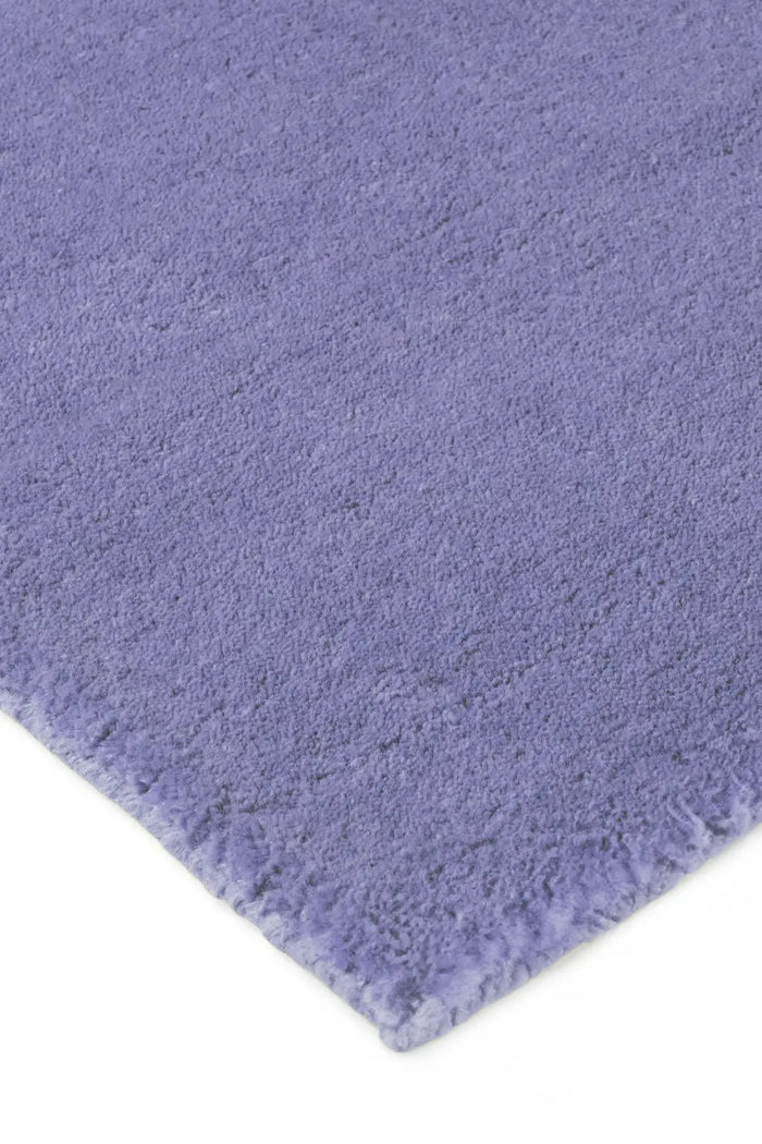 Detail of soft plush purple wool rug with thick, hand-tufted texture