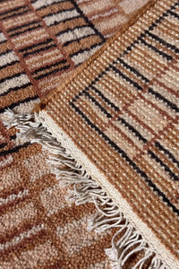 Hand-knotted fringe and corner view of tan and brown checkered wool rug, showcasing craftsmanship and thick natural fiber construction