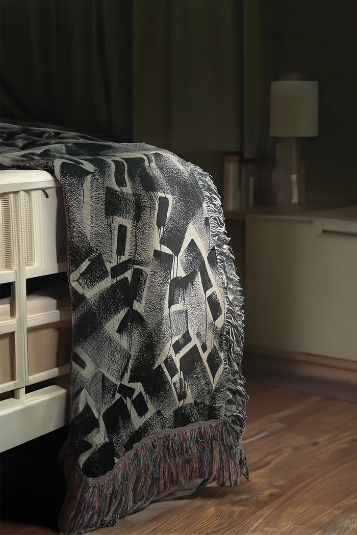 Black and white graphic woven throw blanket with bold abstract patterns.
