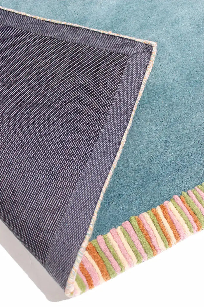 Flatlay of teal green rug with cream, orange, and green waves and striped detail