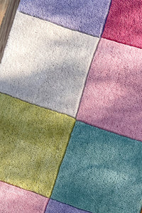 Close-up of the plush colorful wool checkered runner rug, showing the thick tufted texture and vibrant pastel blocks.