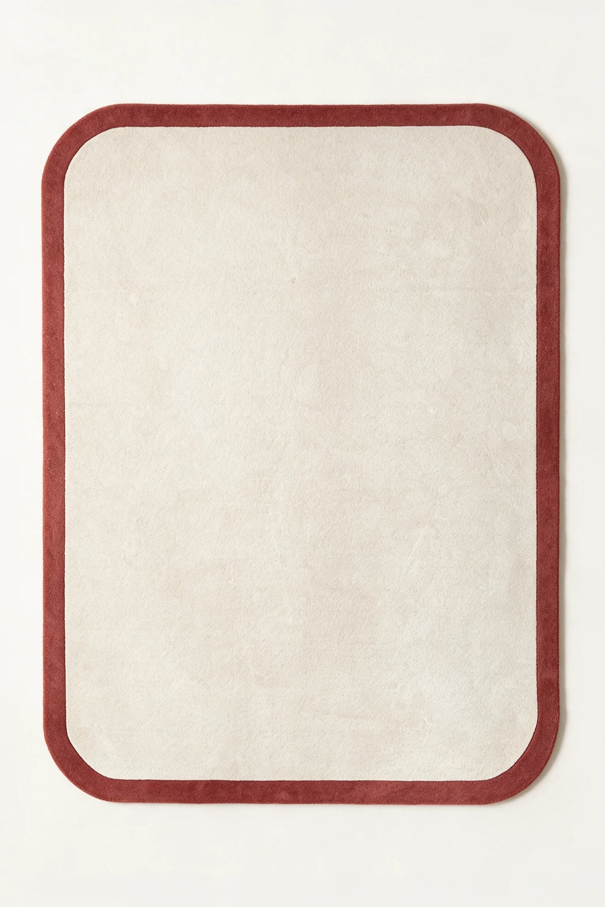 a contour edge hand-tufted wool rug in brick and oat, shown flat from above