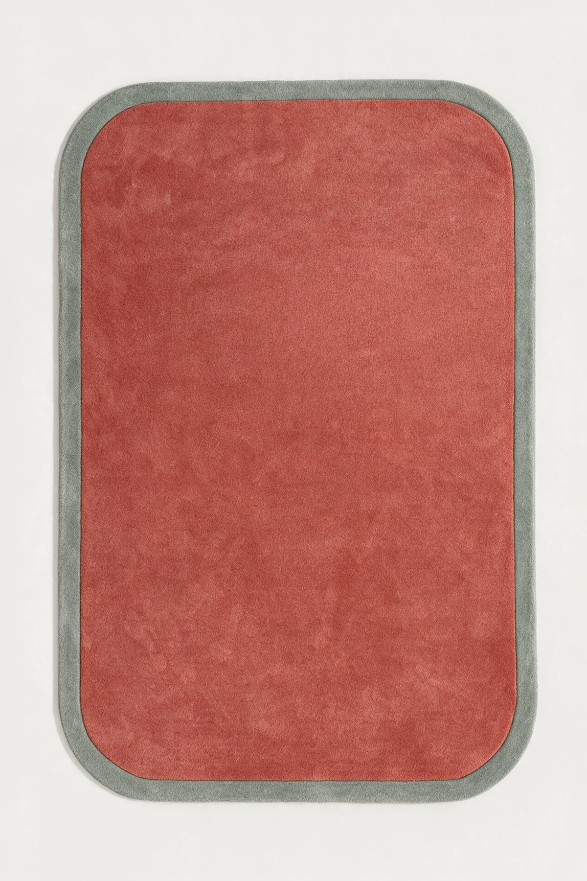 a contour edge hand-tufted wool rug in mist and salmon, shown flat from above