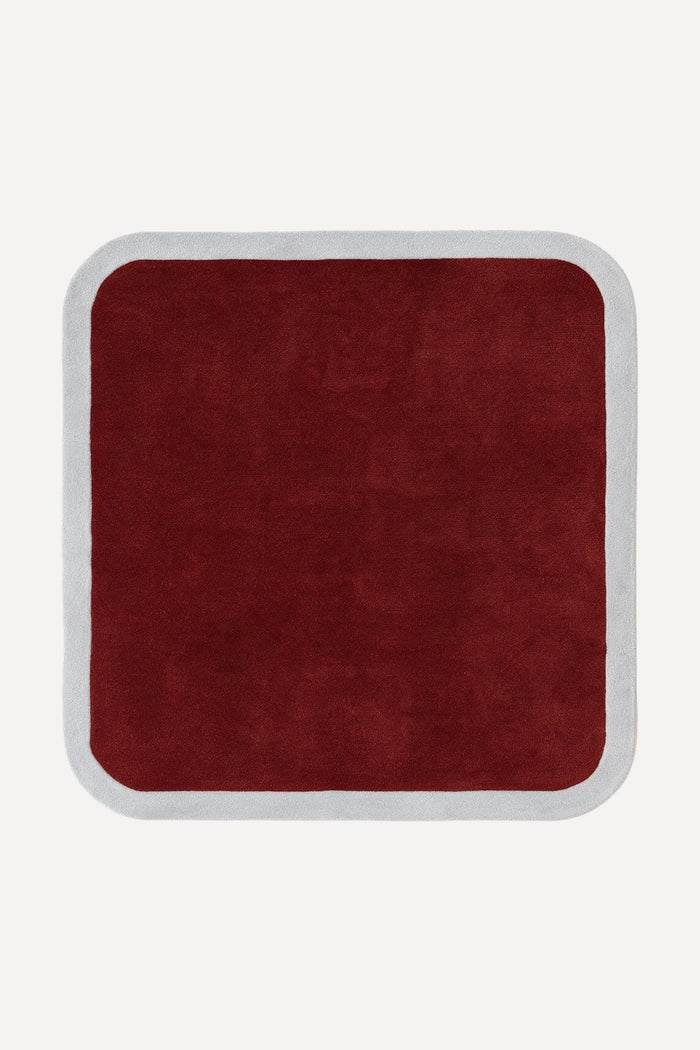 a contour edge square hand-tufted wool rug in burgundy and fog, shown flat from above