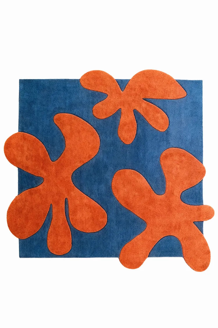 Blue rug with orange abstract flower shapes on a white background
