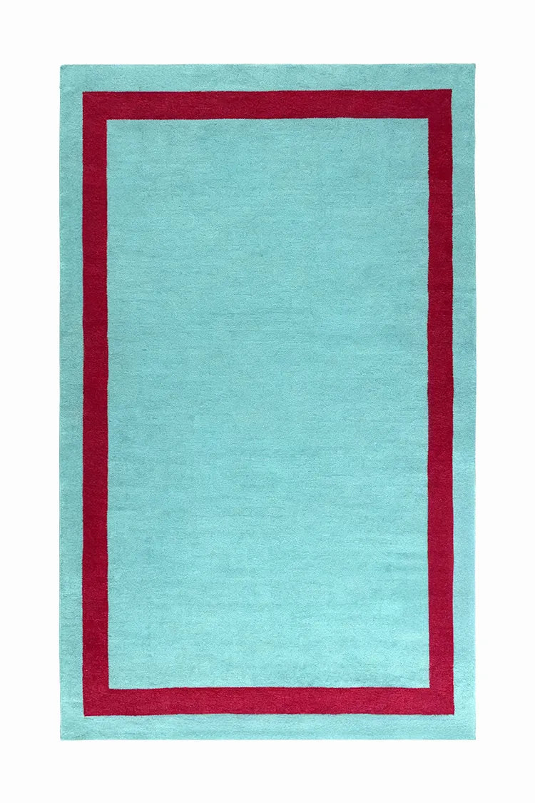 Rectangular turquoise rug with a red border on a white background
