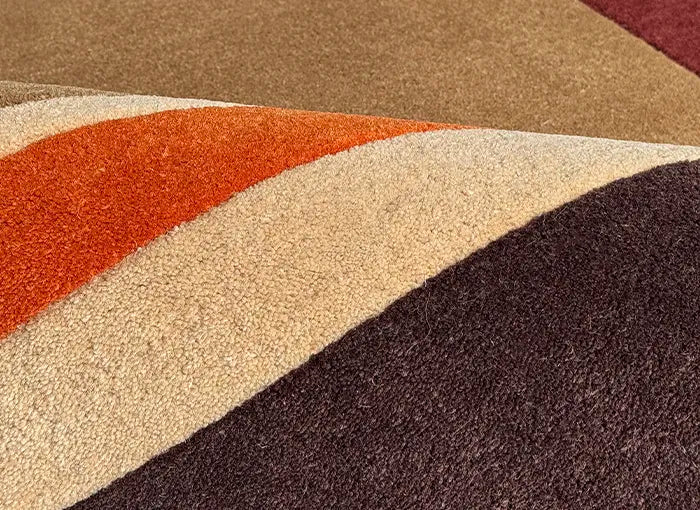 Close-up of a multicolored striped rug with brown, red, beige, and black shades.