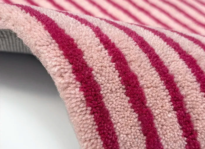 Close-up of a striped rug with pink and red horizontal lines on a white background