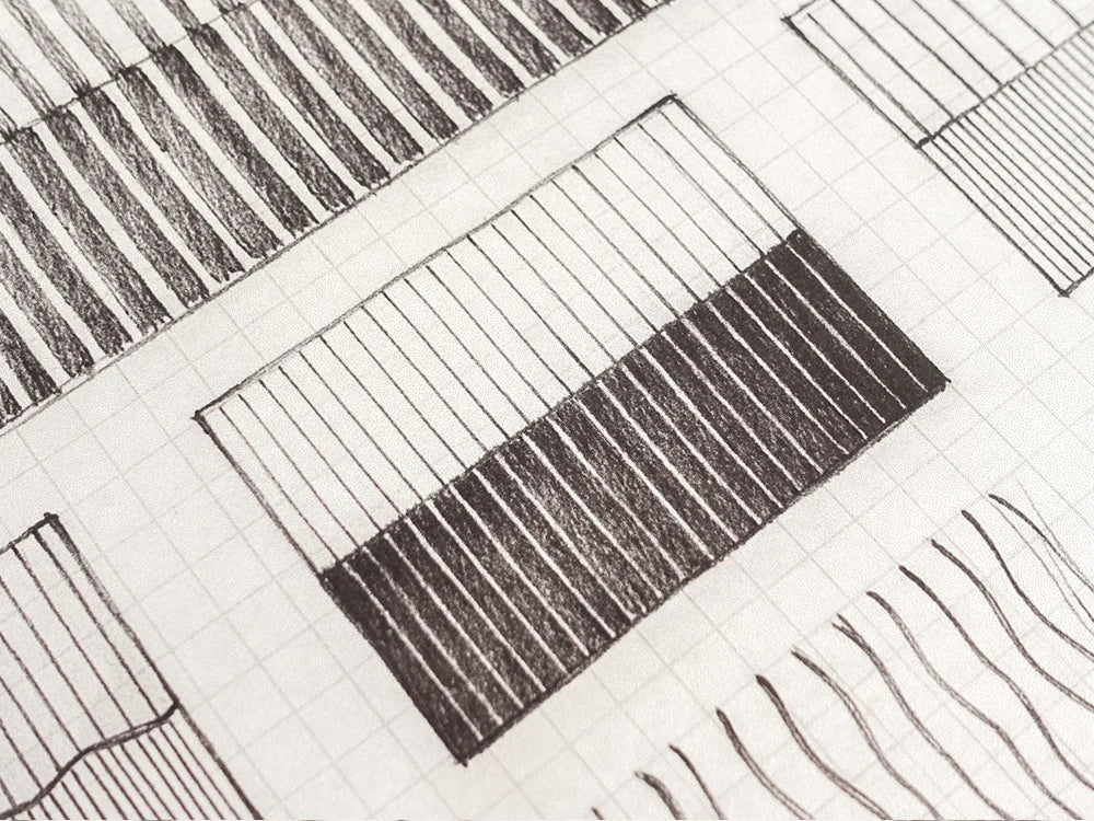 A close-up of a black and white sketch on graph paper, showing geometric shapes and hatched patterns.