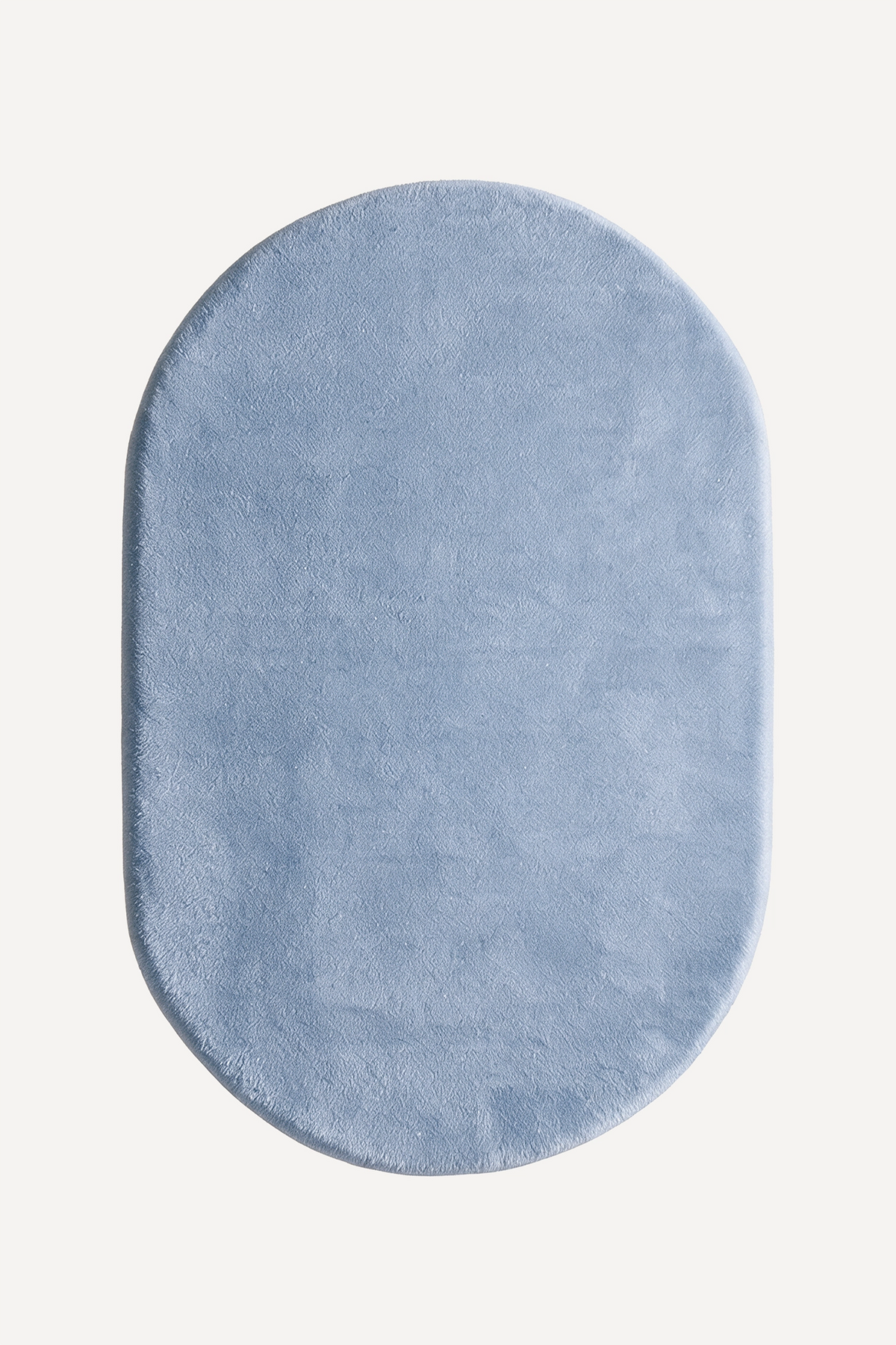 A light blue oval plush rug with a soft, textured surface, shown from a top-down view on a clean off-white background.