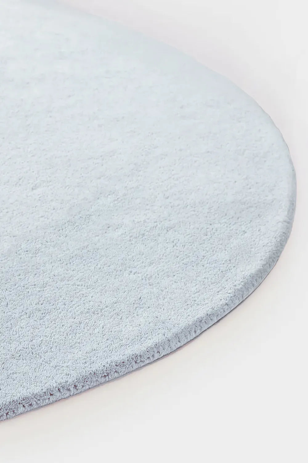 Detail of plush pale blue round wool rug with soft pile