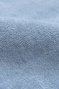 Detail of plush pale baby blue round wool rug with soft pile
