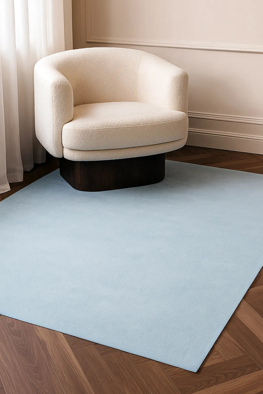 Light blue wool rug in 8x10 size styled under a cream armchair, perfect for minimalist living rooms or bedroom rugs