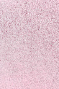 Close-up of thick blush light pink wool rug with plush hand-tufted pile, perfect for high-pile bedroom rugs or luxury nurseries