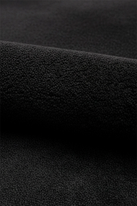 A close-up of a black oval wool rug, shown folded to highlight its tactile quality.