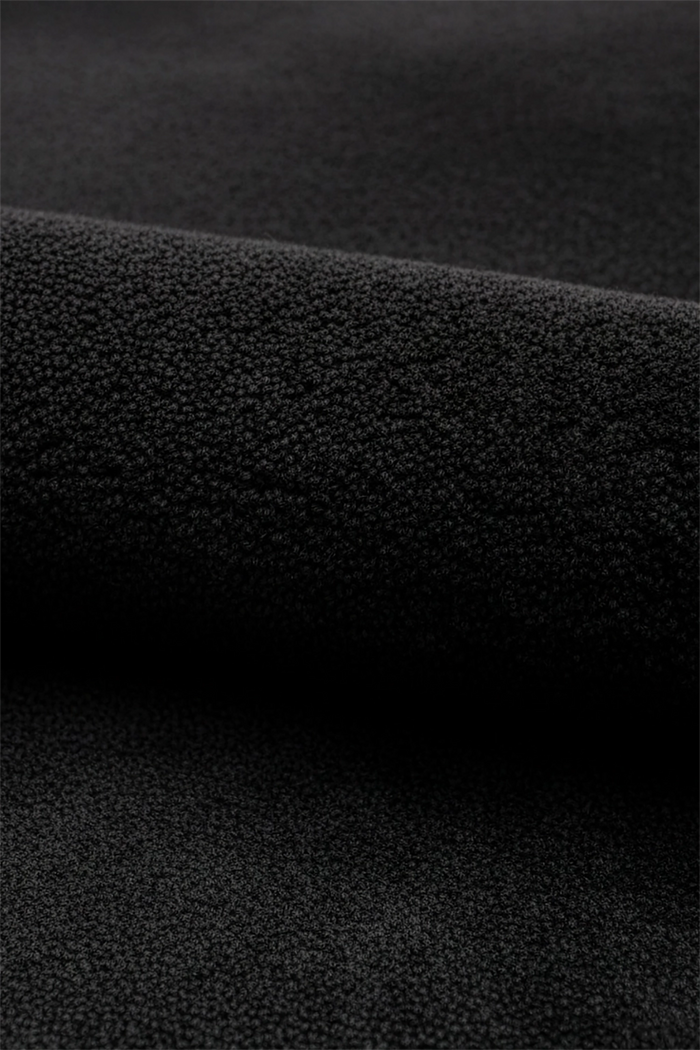 A close-up of a black oval wool rug, shown folded to highlight its tactile quality.