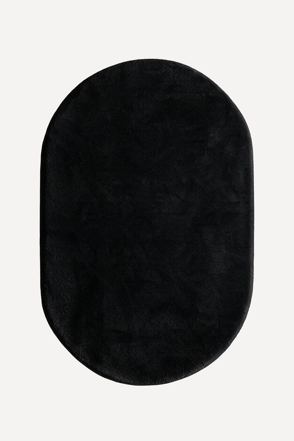 A black oval plush rug with a soft, fuzzy texture, shown from a top-down view on a light off-white background.
