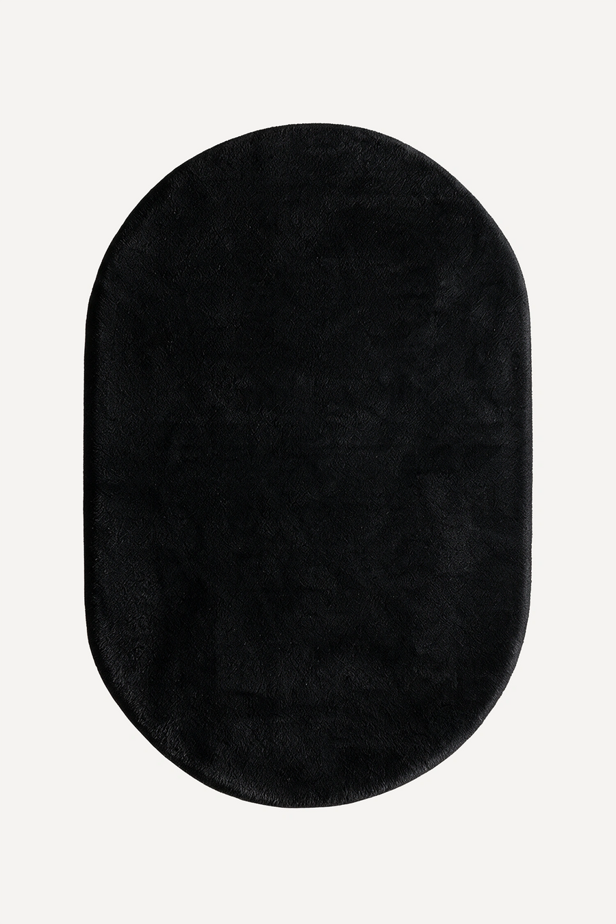 A black oval plush rug with a soft, fuzzy texture, shown from a top-down view on a light off-white background.