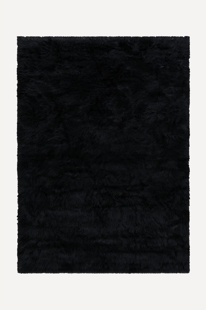 A rectangular black shaggy wool rug shown flat against a light off-white background.
