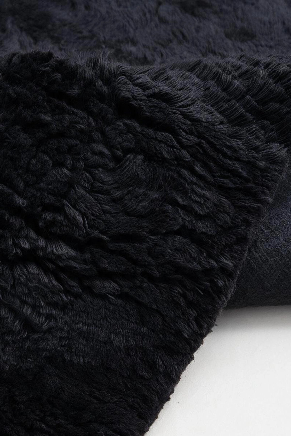 close up view of a black shag wool rug with a plush wool pile