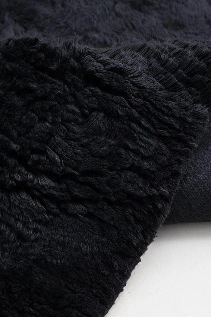 close up view of a black shag wool rug with a plush wool pile