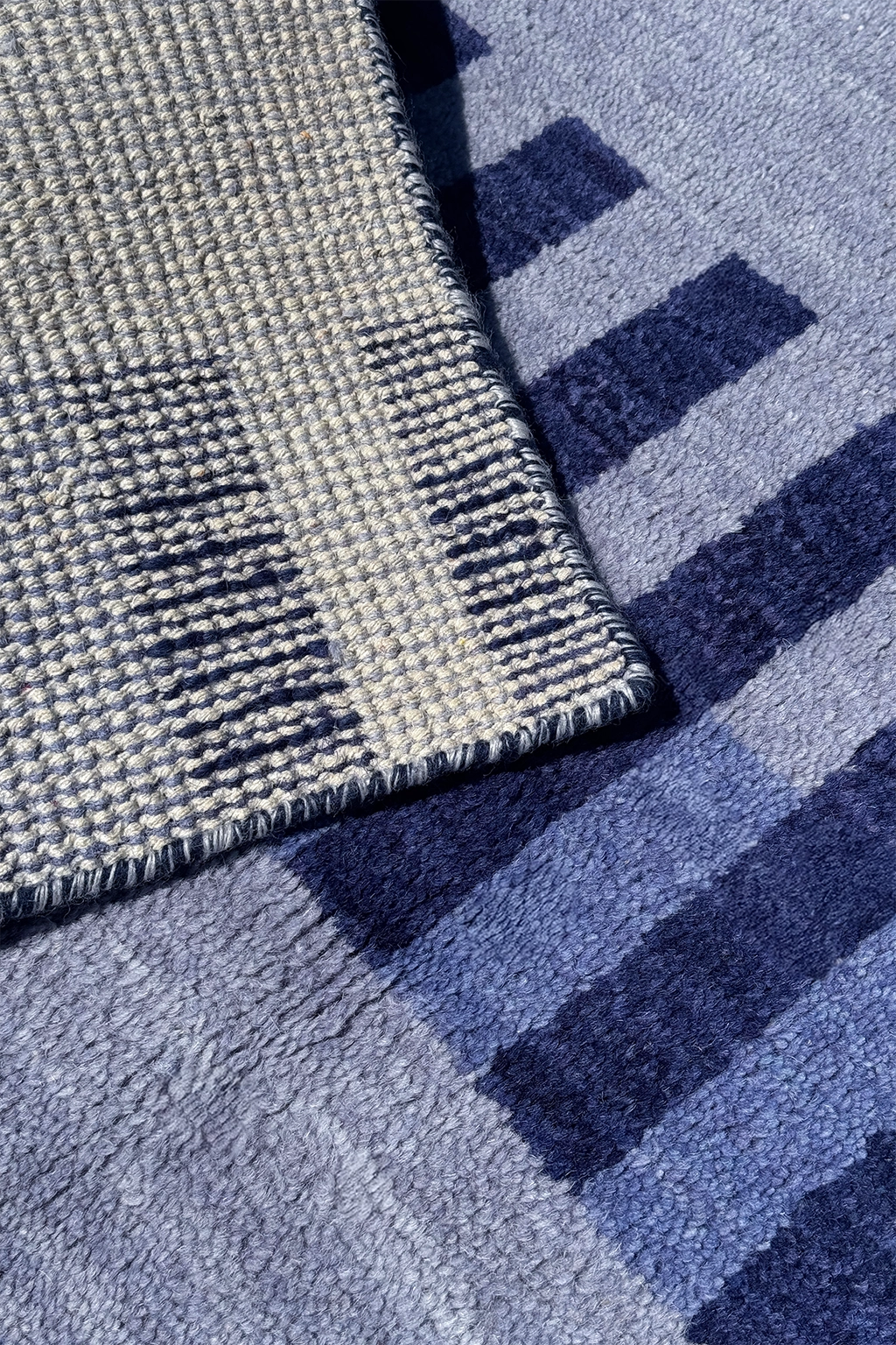 Close-up of a textured runner rug with a geometric pattern in shades of blue, navy, and gray.