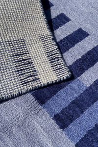 Close-up of a textured runner rug with a geometric pattern in shades of blue, navy, and gray.