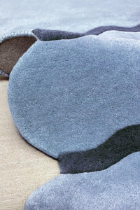 Folded view of modern tufted ripple wool rug, abstract sculptural area rug blue