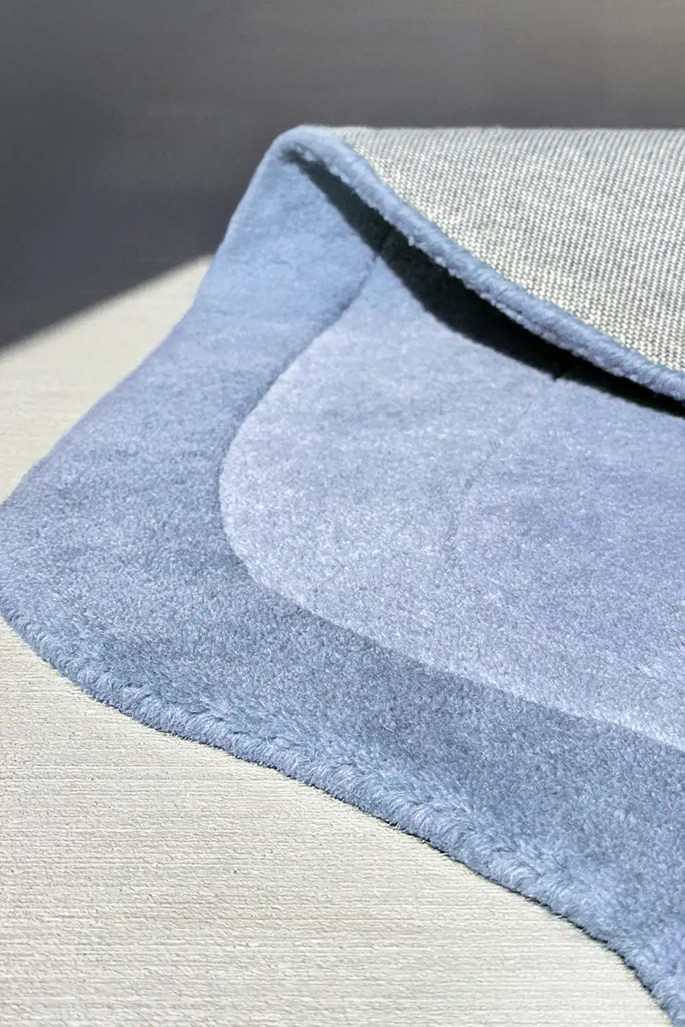 Light blue sculptural wool rug with ripple effect and smooth scalloped border