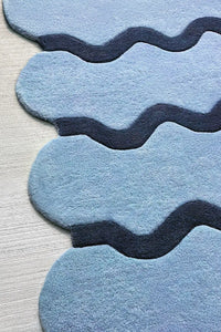 Close-up of baby blue ripple wool rug with navy stripes, funky scalloped irregular shaped rug