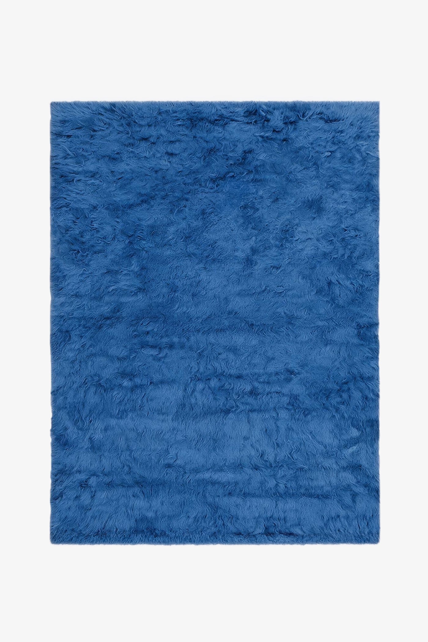 A blue shag rug with a thick, fluffy texture, shown flat against a plain white background.