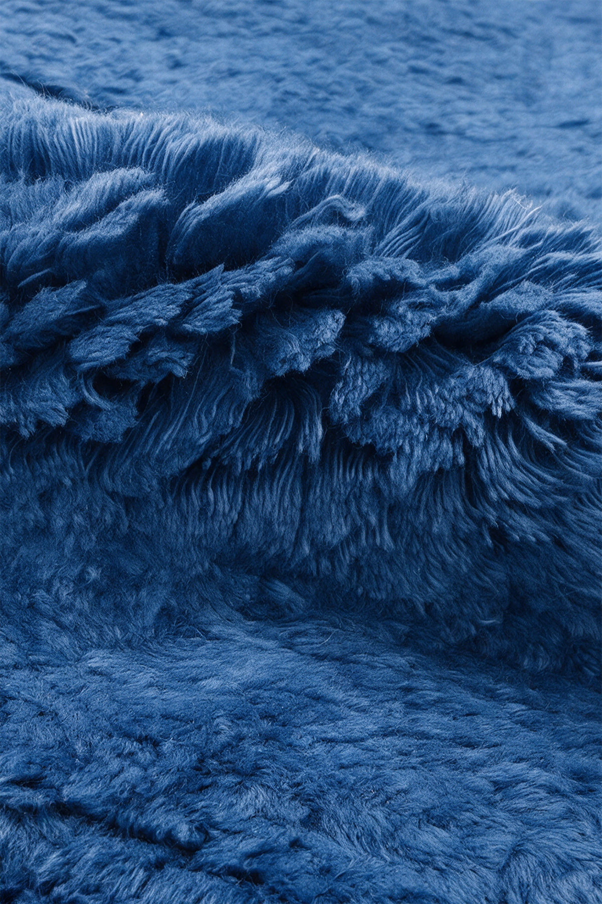 A close-up of a plush, shaggy blue wool rug with dense, fluffy fibers filling the frame.