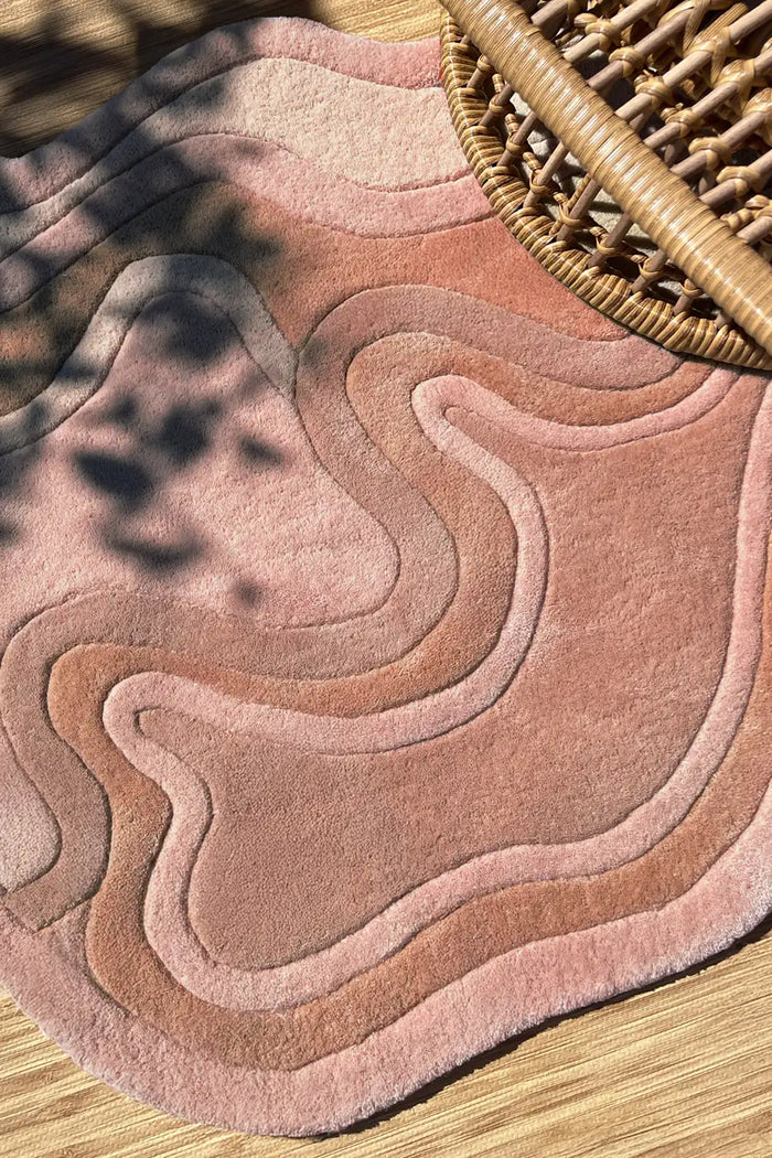 Earthy rust and cream boho area rug in a wavy abstract pattern, handmade wool lifestyle