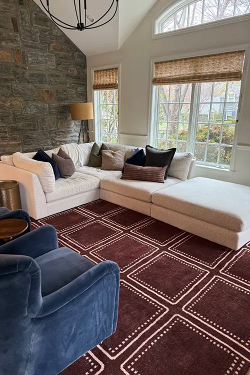 Living room with a sectional sofa, blue armchair, and brown patterned rug.