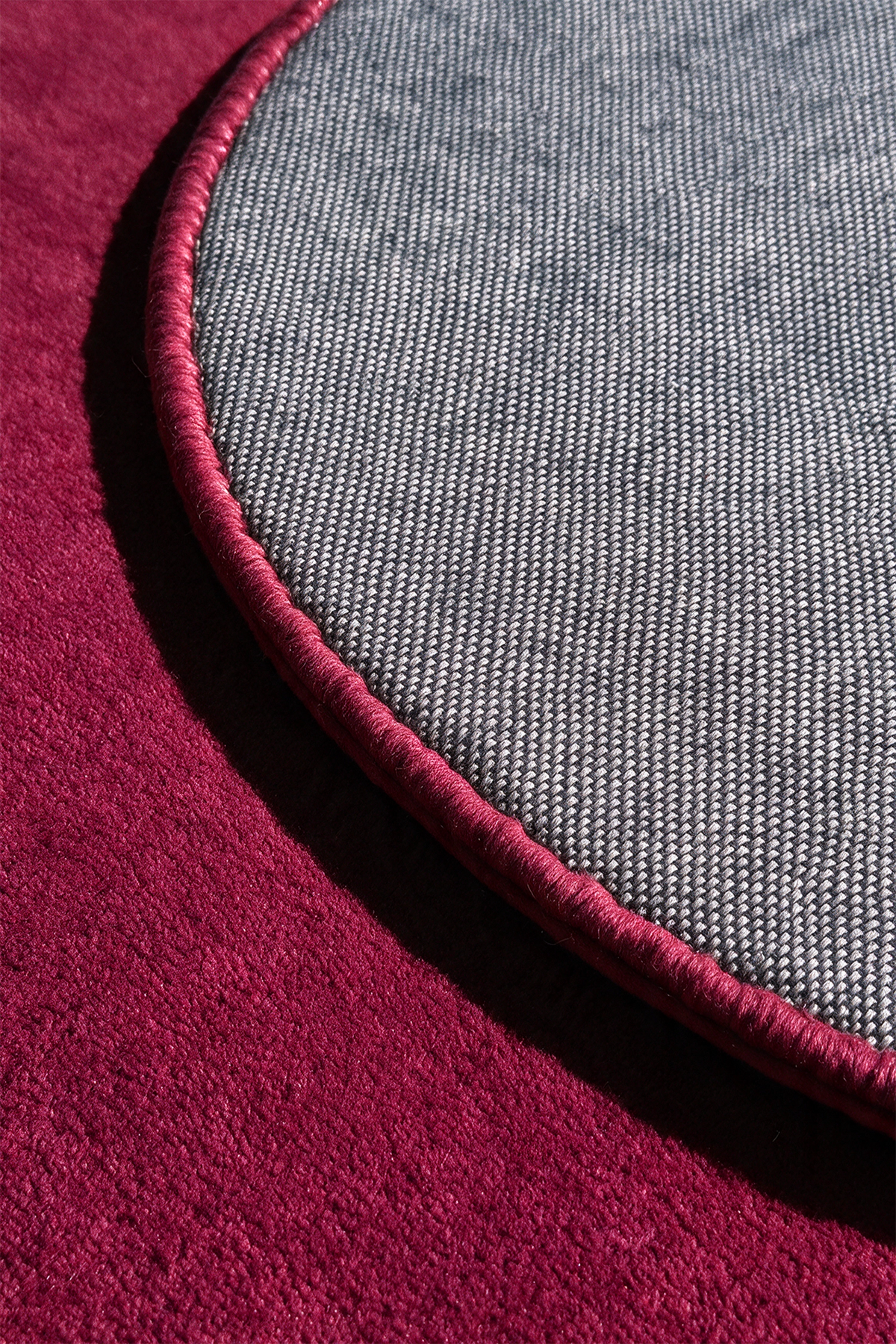 close up view of a burgundy pink round rug backing and binding