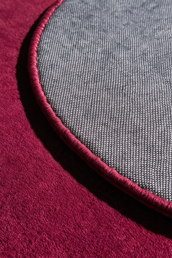 close up view of a burgundy pink round rug backing and binding | Cotton backing