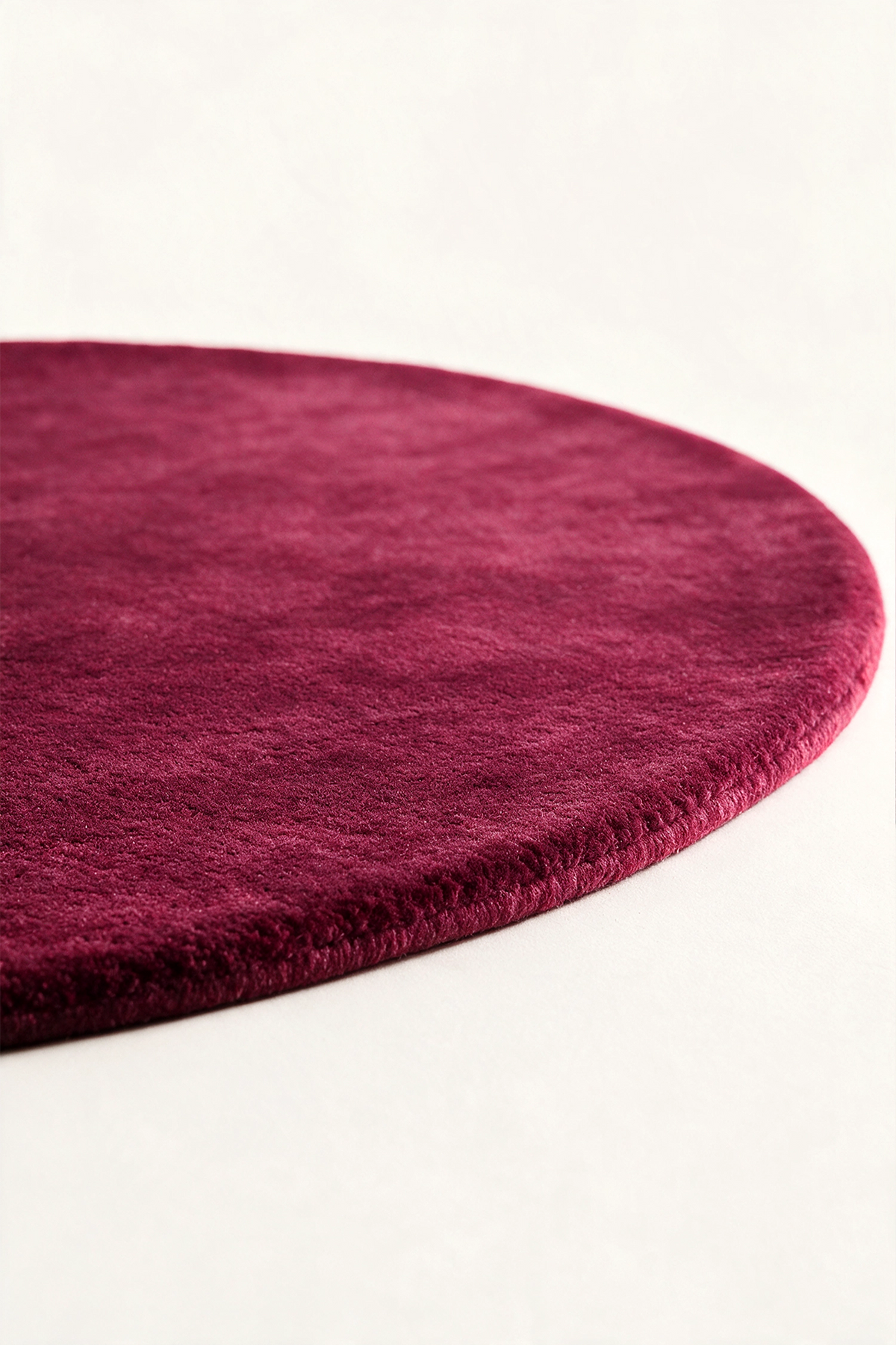 close up of a burgundy round rug viewed from a low angle