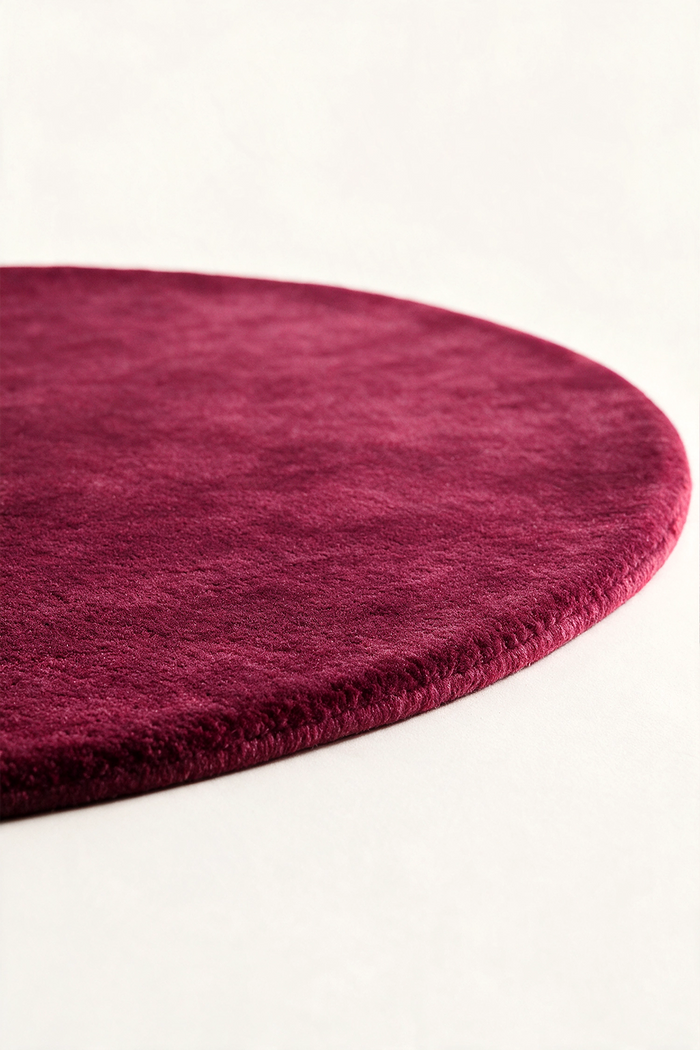 close up of a burgundy round rug viewed from a low angle