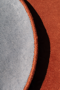close up of the backing and binding of a burnt orange round rug hand-tufted in wool