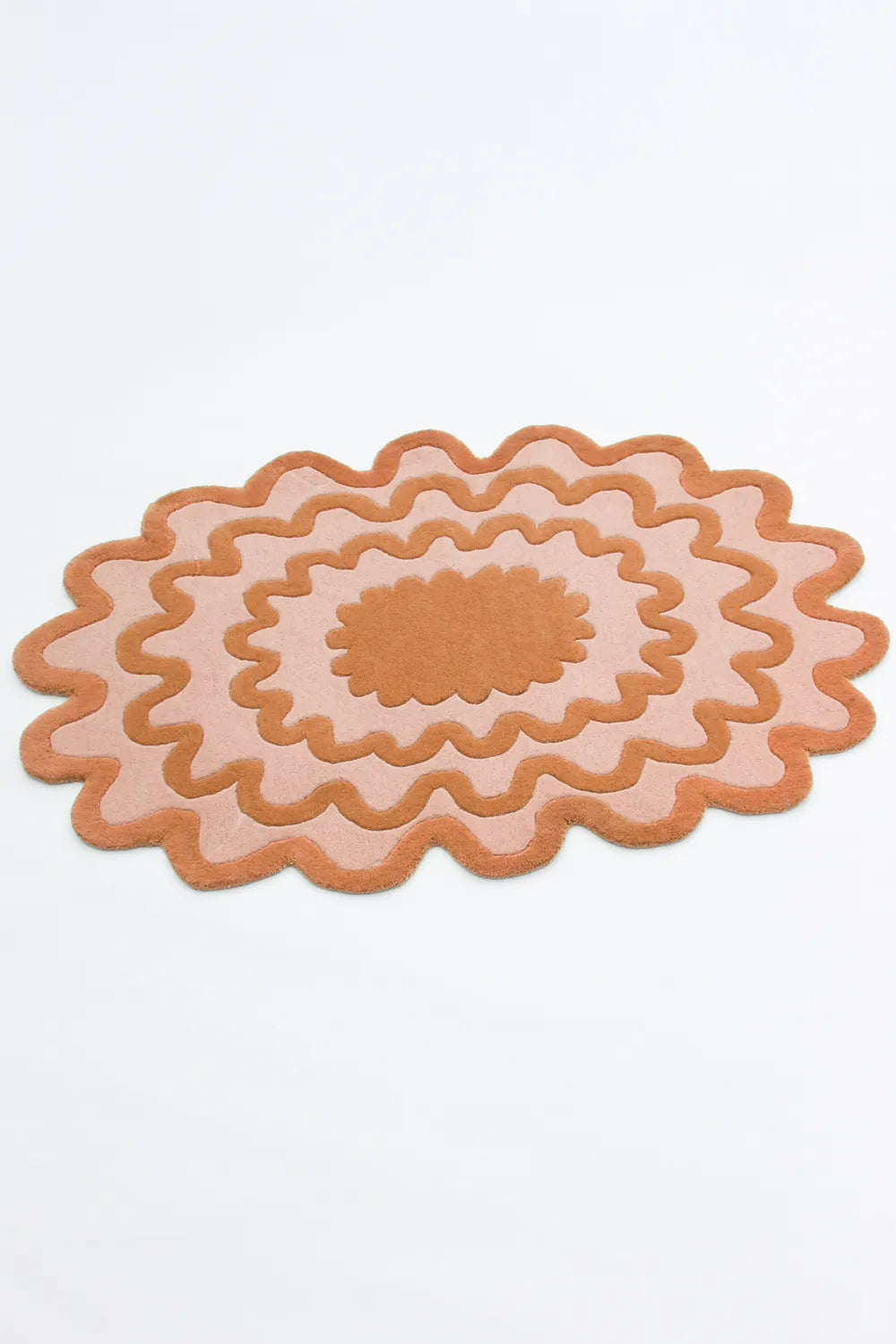 Wavy orange ripple oval rug photographed from side view, funky scalloped wool rug
